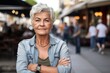 shot of an attractive senior woman standing with her arms crossed while out in public