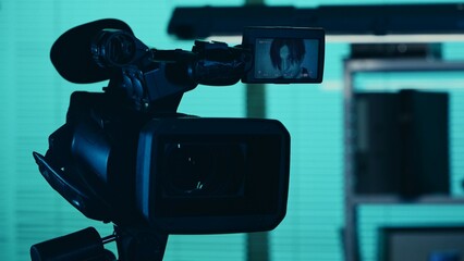 Close up detail shot of the camera filming, recording the face of a suspect, offender, perpetrator or prisoner sitting in an investigation room, looking at the camera.