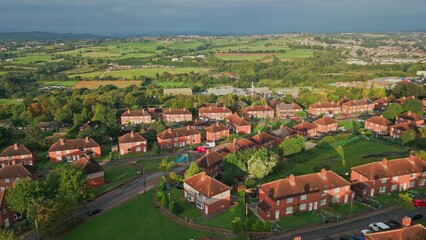 Wall Mural - UK housing district: Aerial view of Yorkshire's red brick council estate, lit by the morning sun, featuring homes and people on the streets.