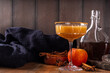 Maple syrup autumn cocktails. Boozy strong alcohol, non-alcoholic mocktail drinks with apple cider, liqueur and spices, on dark wooden background copy space