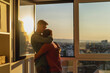 © olezzo - Young cute gay couple hugging in an apartment near the window overlooking the city. LGBT family concept