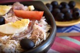 Fototapeta Dmuchawce - Mediterranean rice salad with tuna, olives, eggs, tomatoes, anchovies close-up