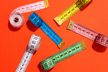 Colorful Measuring Tapes Top View On Bright Red Background