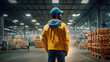 © redflower - Back view of a worker wearing a yellow hat in a warehouse