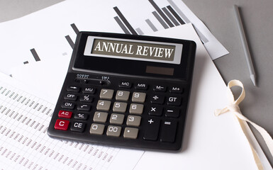 Poster - ANNUAL REVIEW text on calculator with chart on grey background