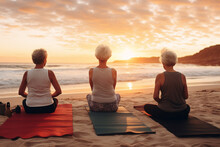 A Group Of Senior Happy Woman Is Doing Yoga Exercises Relaxed And Mindfull With A Yoga Mat On A Beautiful Beach At Sunset