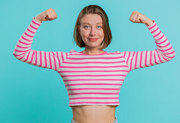 Wall Mural - I am strong and independent. Young woman showing biceps and looking confident, feeling power strength to fight for rights, energy to gain success win. Girl isolated alone on blue studio background