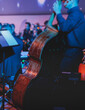 Concert view of violoncello player with vocalist and musical orchestra band, during jazz concert, performing music, violoncellist cello jazz player on stage, old retro vintage contrabass