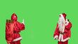 Leinwandbild Motiv Saint nick pushing object to left or right sides, showing dismiss gesture over greenscren in studio. Santa claus embodiment doing rejection sign, christmas eve celebration concept.