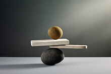Generative AI Image Of Pebbles Balancing On White Plank On Round Stone With Shade And Placed On Rock On Gray Surface Against Gray Wall In Day