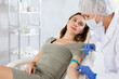 © JackF - Thankful calm woman laying on exam table receiving injection in vein by senior doctor.