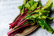 Beet tops on a metal dish on a gray concrete background