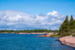 georgian bay dramatic blue sky and white clouds  with scoured rock and green trees in the fore ground where a young man loads a red kayak room for text