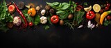 Top view of food ingredients on black slate table with spices herbs and vegetables