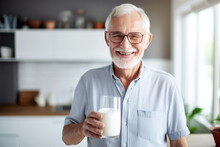 Portrait Of An Elderly Man Smiling With Gray Hair On His Head And Beard With Glasses Holding A Glass With Milk In His Hand On The Background Of The Kitchen.generative Ai

