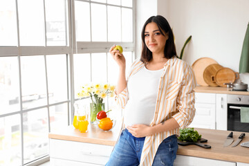 Poster - Young pregnant woman with apple in kitchen