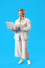 Poster - Mature female programmer working with laptop on blue background