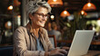 Senior old woman using glasses working with laptop in cafe created with Generative AI Technology