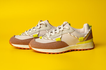 Poster - Beige sport running shoes on yellow studio background