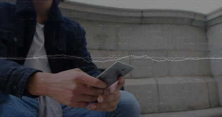 Wall Mural - Animation of multiple graphs over low angle view of biracial man sitting and using smartphone