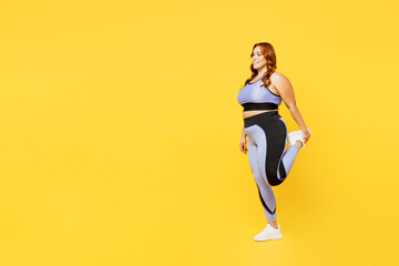 Wall Mural - Full body side view young chubby plus size big fat fit woman wear blue top warm up training raise up leg do stretch exercises isolated on plain yellow background studio home gym orkout sport concept