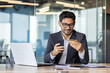 © Liubomir - Young successful man at workplace inside office with bank credit card and phone, counting online services and buying in online store.