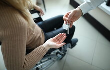 Woman In Wheelchair Is Given Keys To House. Getting Social Housing For Disabled People Concept