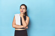 © Asier - Sporty woman with towel on blue studio looking sideways with doubtful and skeptical expression.