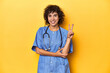 Curly-haired Caucasian woman nurse on yellow studio showing number two with fingers.
