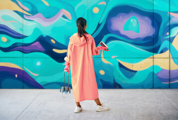 Back view of female street artist looking to the graffiti wall with her paintings