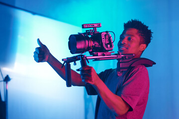 Wall Mural - African American professional cameraman shooting photo for content in studio