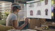 © Framestock - Woman in VR headset chooses clothes in online store chilling at home. 3D futuristic hologram shows widgets in user menu and clothing store website interface. VFX animation. Concept of online shopping.