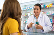 © Jestercine - Young Asian pharmacist talking with customer at pharmacy counter. She tells customers about drug information at the pharmacy.