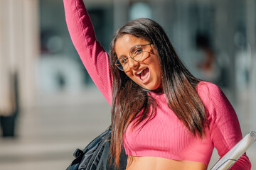 student girl with books and backpack at school celebrating euphoric