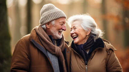 Wall Mural - Senior couple enjoying life outdoors in autumn. Elderly woman and man laughing and looking each other. Blurry forest background.