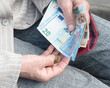 Euro banknotes in the hands of an elderly woman.	