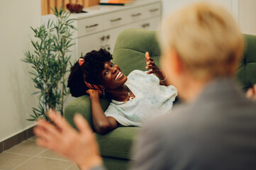 Wall Mural - Woman is lying on the couch at a psychotherapist's office and having an individual session.