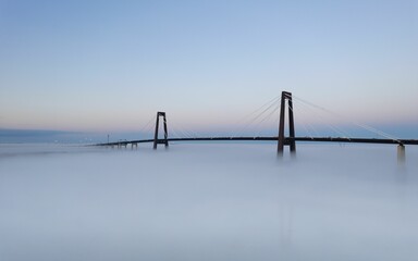 Canvas Print - Tranquil, blue-sky scene featuring the Hale Boggs Memorial Bridge shrouded in foggy mist