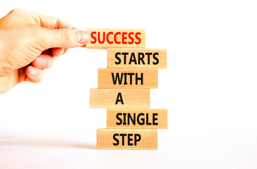 Wall Mural - Success symbol. Concept words Success starts with a single step on wooden block. Beautiful white table white background. Businessman hand. Business success starts with single step concept Copy space