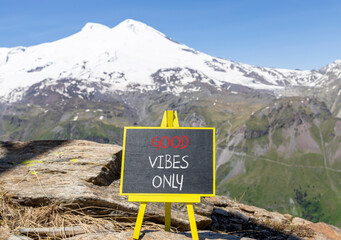 Wall Mural - Good vibes only symbol. Concept word Good vibes only on beautiful black chalk blackboard. Beautiful mountain Elbrus blue sky background. Business motivational good vibes only concept. Copy space.
