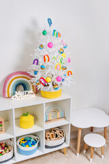 Wall Mural - Children's room with littel white christmas tree decorated bright and colorful decorations, rainbow, balls and toys. Merry Christmas and Happy Holidays!