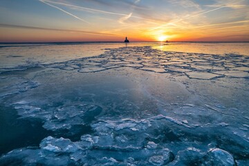 Poster - Stunning landscape featuring a tranquil lake partially frozen illuminated by the warm morning sun