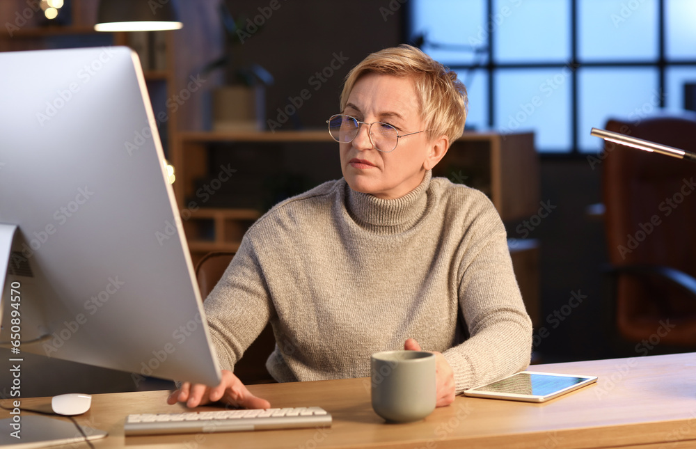 Mature female programmer working in office at night