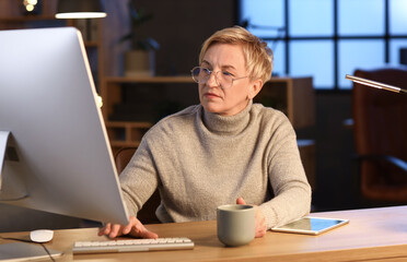 Mature female programmer working in office at night