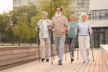 Canvas Print - Group of senior people performing Nordic walking outdoors. Low angle view