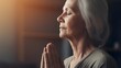 An middle-aged woman with her eyes closed, hands clasped in devout prayer. Meditating. Engaged in a process of self-healing.