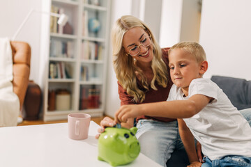 Wall Mural - Mother is teaching er young son about saving money in a fun way.