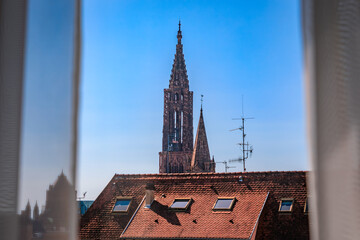 Poster - Grande Ile city skyline through a window, tiled roofs and spires of Notre Dame Cathedral and Eglise du Temple Neuf church, Strasbourg, Alsace, France