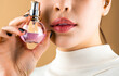 © Yevhen - Woman presents perfumes fragrance. Sexy lips. Pink lip. Close up of sexy plump soft lips with dark red lipstick. Beautiful girl using perfume. Woman with bottle of perfume