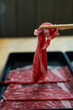 Man holding rare slice beef by chopsticks for boiling in Shabu hot pot, close up